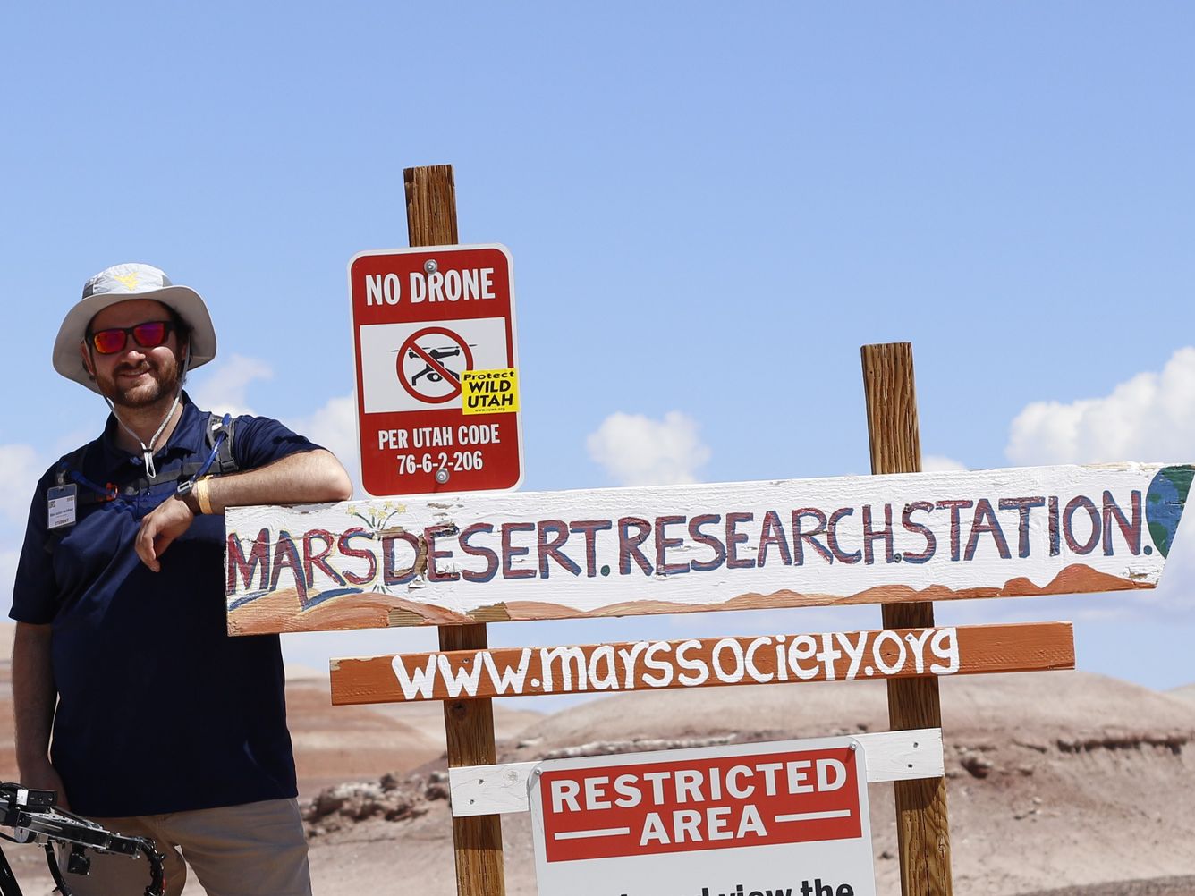 Person leaning on Mars Desert Research Station sign